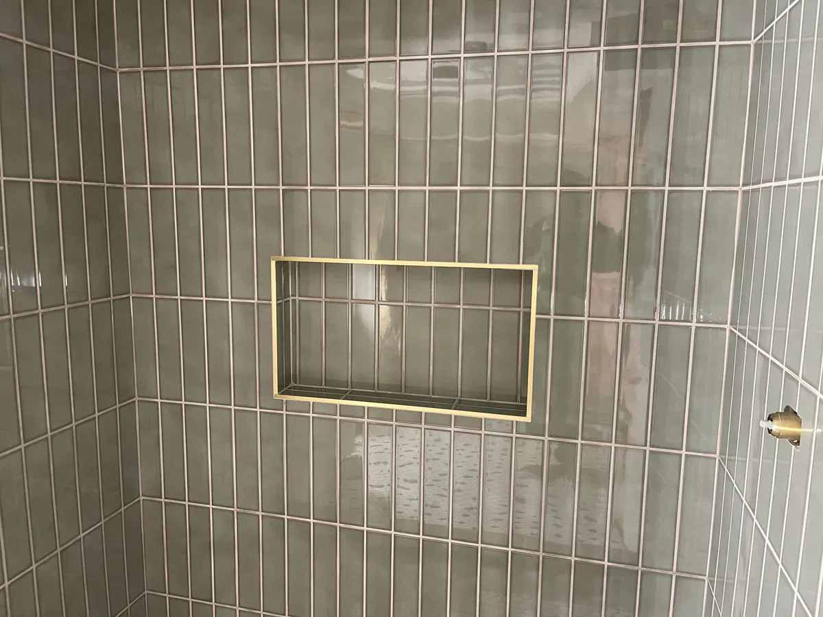 Green tiled wall with gold-framed reflection mirror